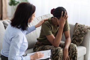 female-psychologist-comforting-black-soldier-lady-therapy-session-office